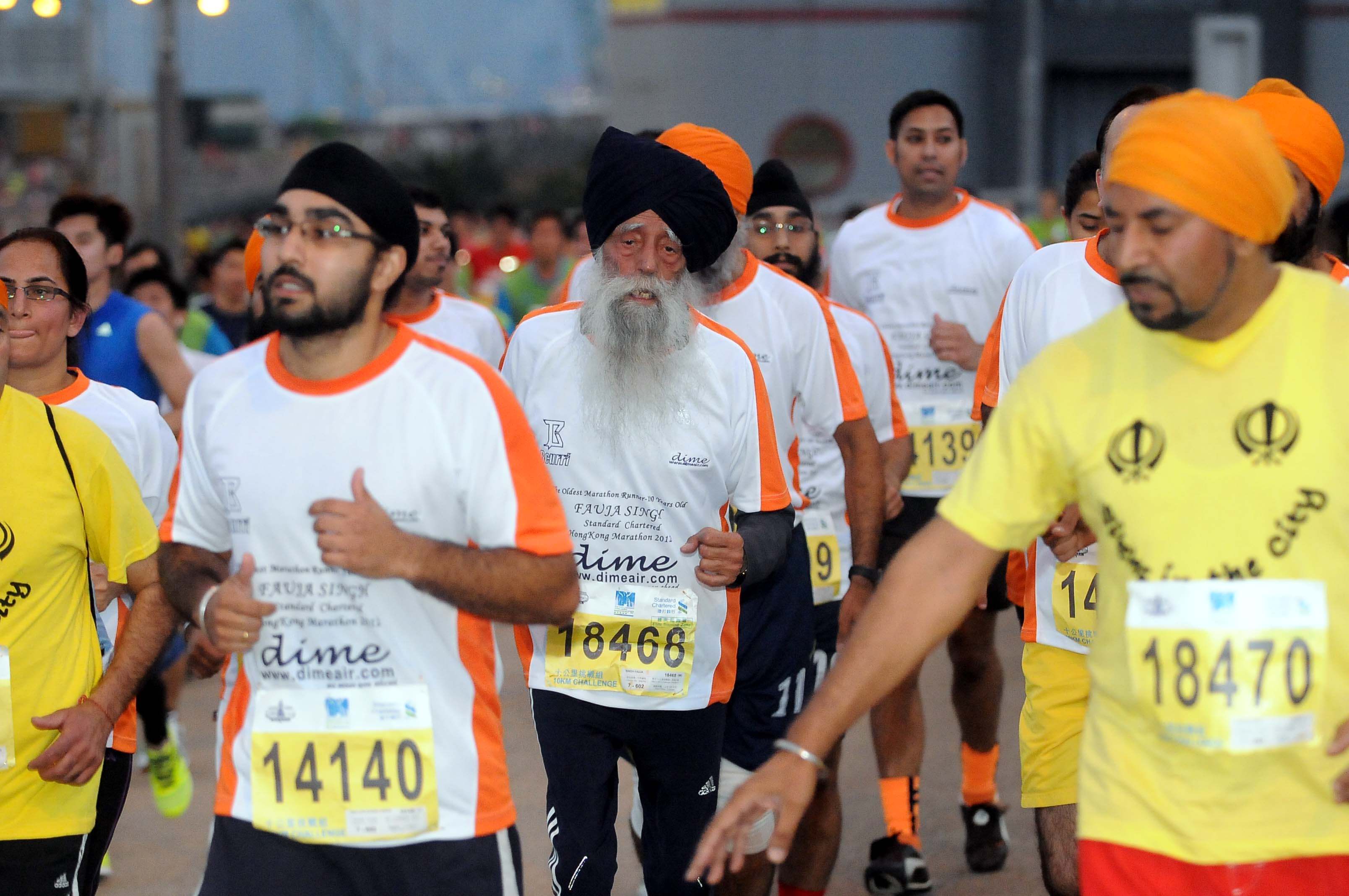 Fauja Singh BEM running with the Sikhs In The City community at a marathon