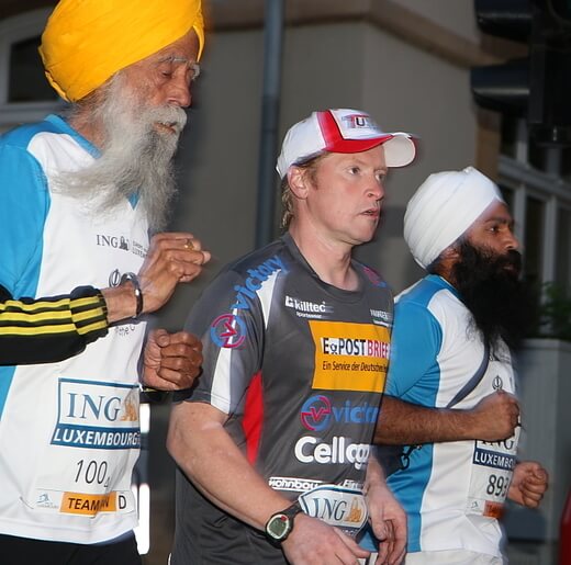 Fauja Singh BEM running alongside fellow runners